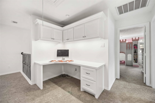 office space featuring light carpet, built in desk, visible vents, and baseboards