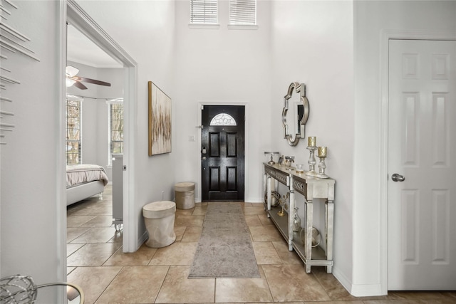 foyer entrance with a ceiling fan and baseboards