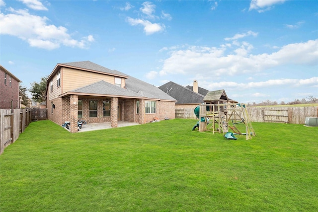 back of property with a patio area, a yard, brick siding, and a playground