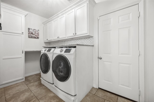 laundry area with light tile patterned floors, independent washer and dryer, cabinet space, and baseboards