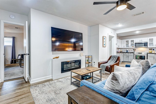 living room featuring ceiling fan and light hardwood / wood-style flooring