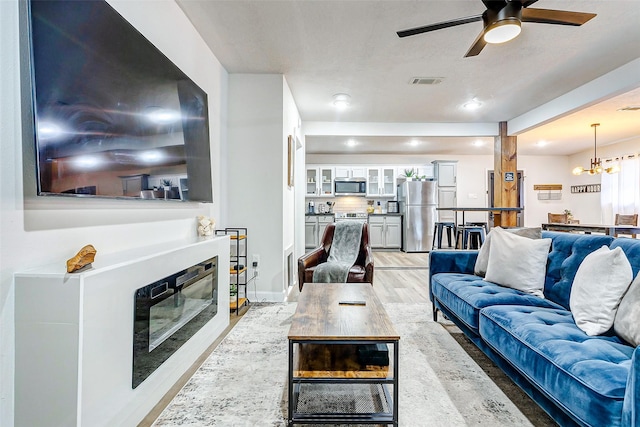 living room with hardwood / wood-style floors and ceiling fan with notable chandelier