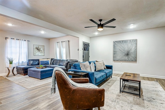 living room featuring ceiling fan, a textured ceiling, and light hardwood / wood-style floors