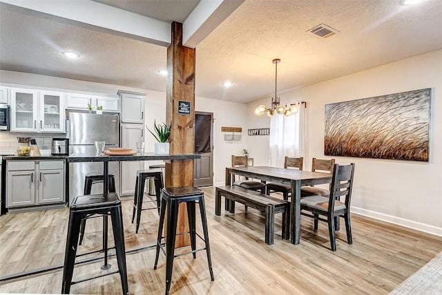 dining space featuring light hardwood / wood-style flooring, a chandelier, and a textured ceiling