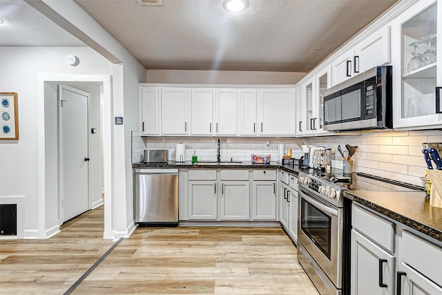 kitchen with white cabinetry, sink, stainless steel appliances, and light wood-type flooring