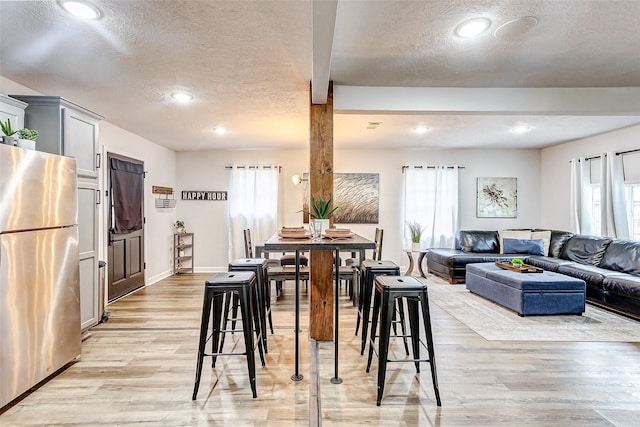 dining space with a textured ceiling and light hardwood / wood-style flooring