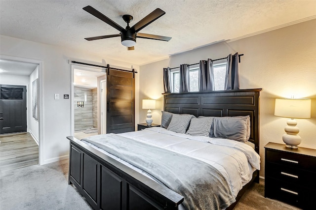 bedroom featuring ceiling fan, carpet floors, a barn door, and a textured ceiling