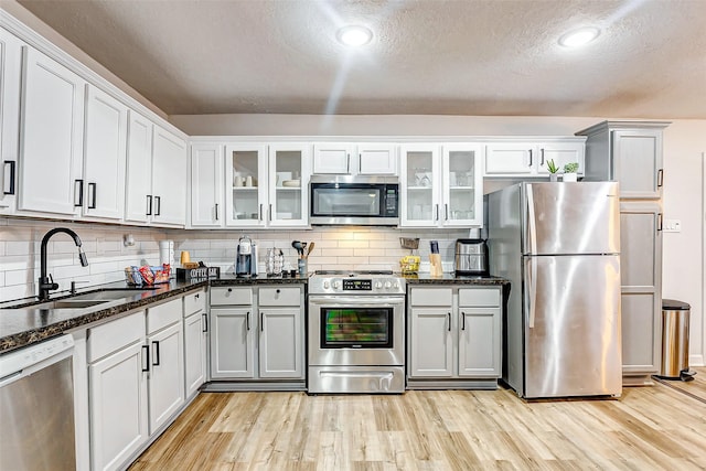 kitchen featuring tasteful backsplash, appliances with stainless steel finishes, sink, and light hardwood / wood-style flooring