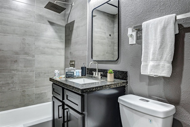 full bathroom featuring tiled shower / bath, vanity, and toilet