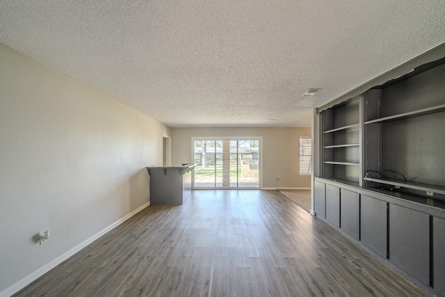 unfurnished living room featuring dark wood-type flooring and a textured ceiling