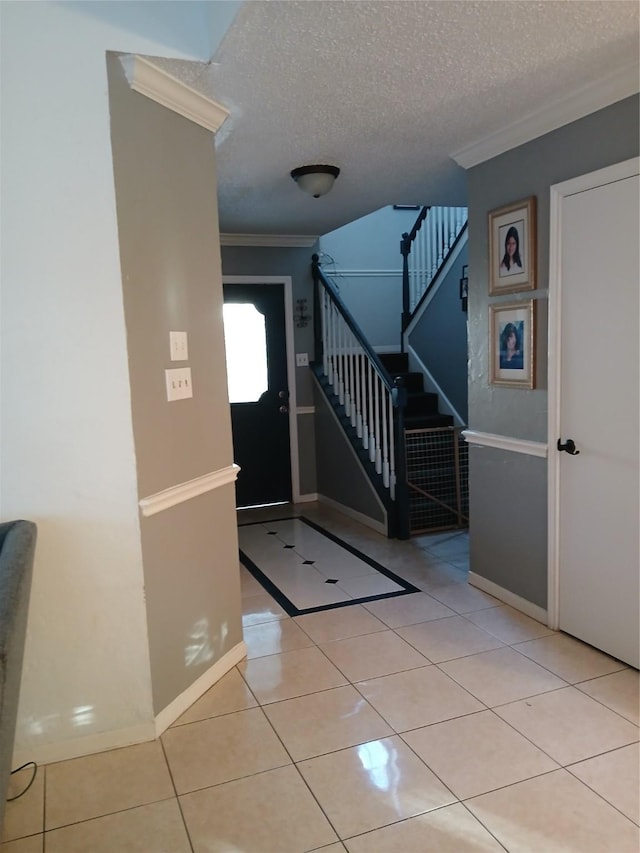 tiled entrance foyer featuring ornamental molding and a textured ceiling