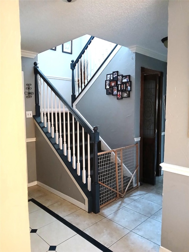 stairway featuring tile patterned flooring, crown molding, and a textured ceiling