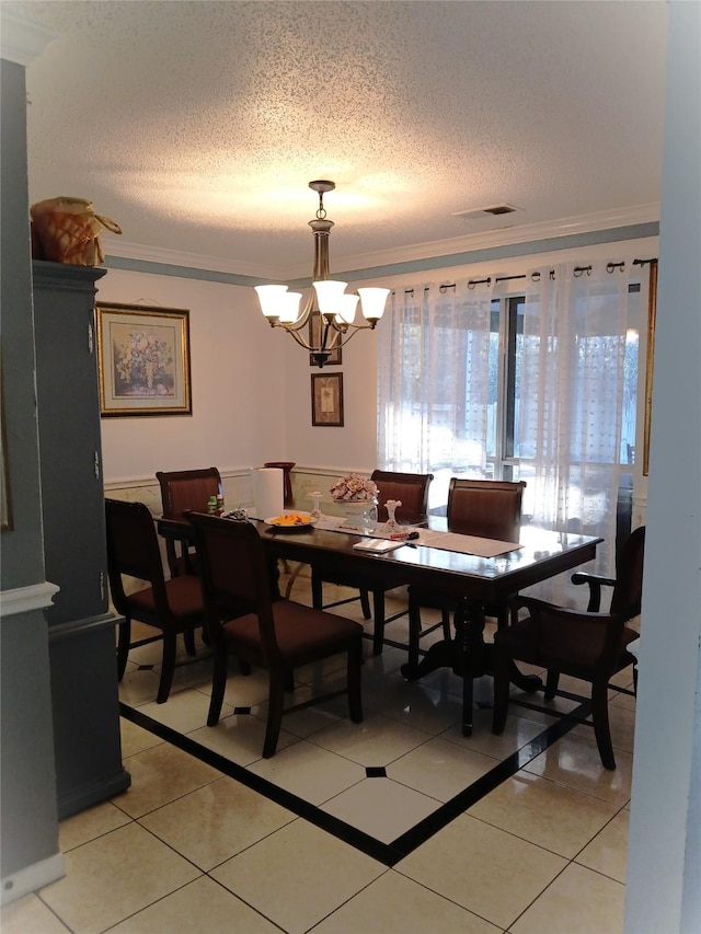 tiled dining space with crown molding, a textured ceiling, and a notable chandelier