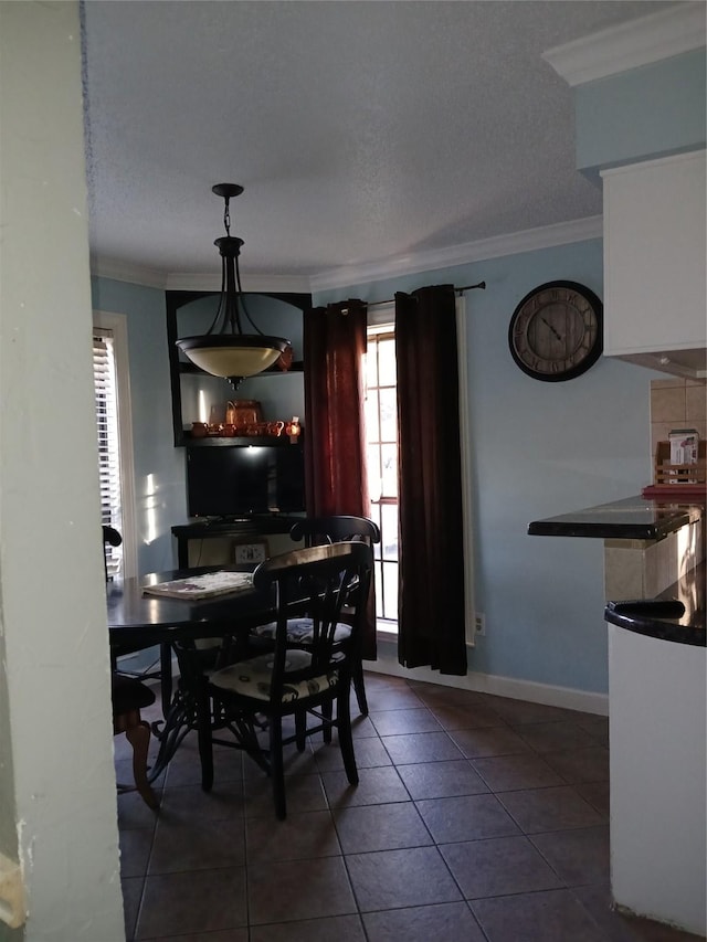 dining space with crown molding, dark tile patterned flooring, and a textured ceiling