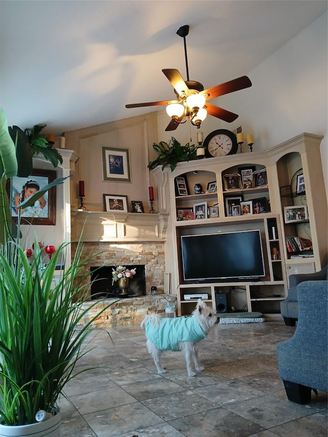 living room featuring ceiling fan, lofted ceiling, and a stone fireplace