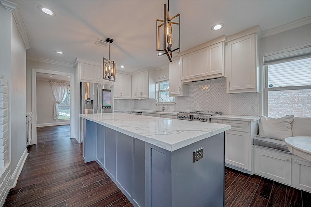 kitchen with white cabinetry, sink, decorative light fixtures, and range