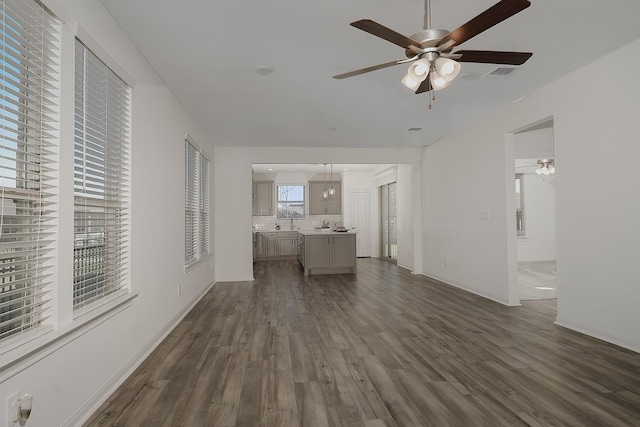 unfurnished living room featuring dark hardwood / wood-style floors, sink, and ceiling fan