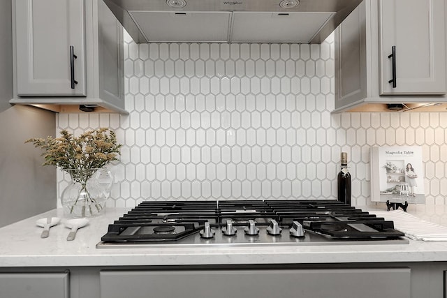 kitchen featuring stainless steel gas cooktop, decorative backsplash, and exhaust hood