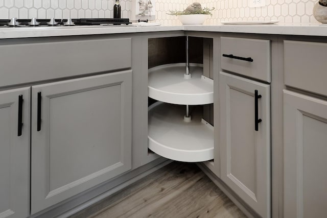 details featuring light stone counters, light wood-type flooring, and backsplash