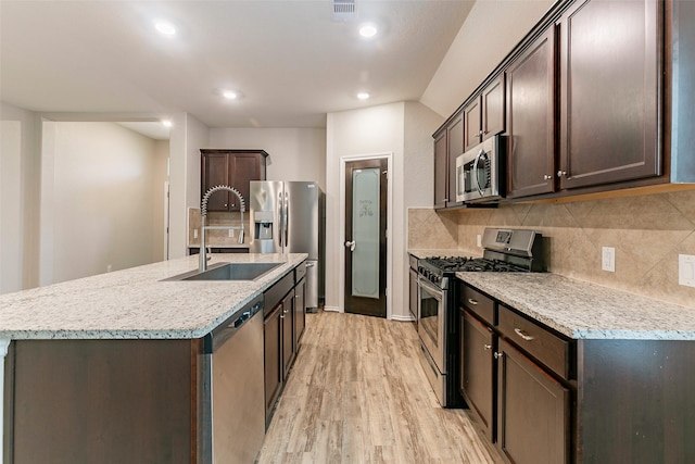 kitchen featuring tasteful backsplash, sink, stainless steel appliances, and an island with sink