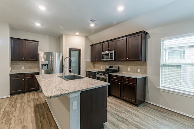 kitchen featuring a kitchen island with sink, sink, stainless steel appliances, and light hardwood / wood-style floors