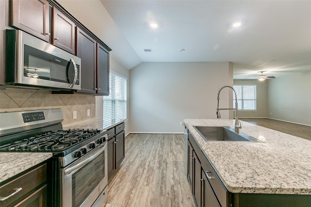 kitchen with sink, light hardwood / wood-style flooring, backsplash, stainless steel appliances, and an island with sink