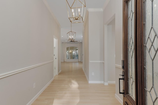 corridor with ornamental molding, a chandelier, and light hardwood / wood-style flooring