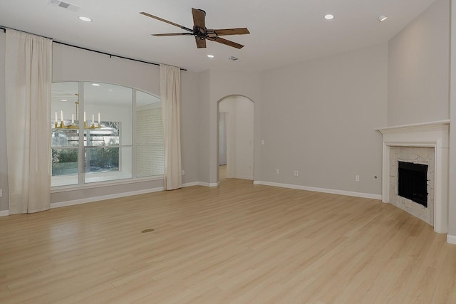 unfurnished living room featuring ceiling fan, light wood-type flooring, and a high end fireplace