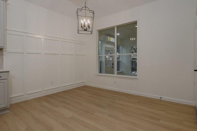 unfurnished dining area featuring an inviting chandelier and light hardwood / wood-style floors