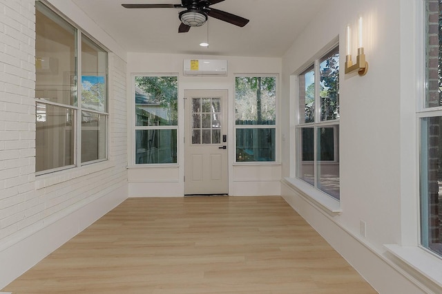 unfurnished sunroom featuring ceiling fan and a wall mounted AC