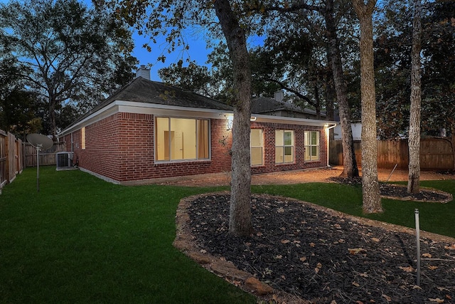 exterior space with central AC unit and a lawn