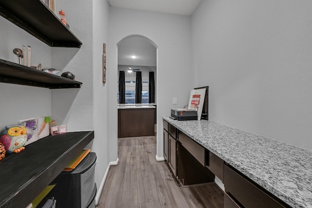 interior space with dark brown cabinetry, light stone countertops, and light hardwood / wood-style flooring