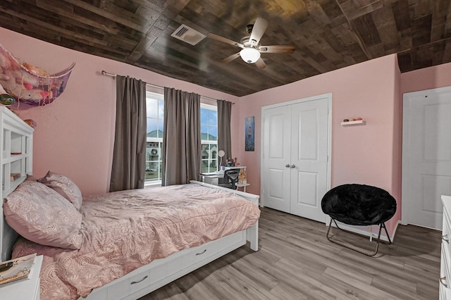 bedroom featuring wood ceiling, light hardwood / wood-style flooring, a closet, and ceiling fan