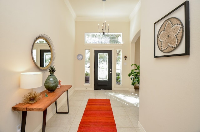 tiled entryway featuring an inviting chandelier, crown molding, and a high ceiling