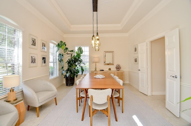 dining space featuring a raised ceiling, ornamental molding, light tile patterned floors, and a chandelier