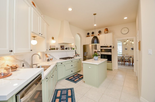 kitchen featuring sink, hanging light fixtures, appliances with stainless steel finishes, a kitchen island, and backsplash