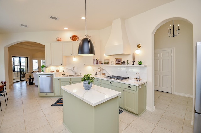 kitchen with appliances with stainless steel finishes, sink, custom exhaust hood, hanging light fixtures, and green cabinetry