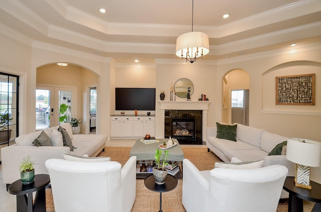 living room with french doors, a tile fireplace, ornamental molding, and a tray ceiling