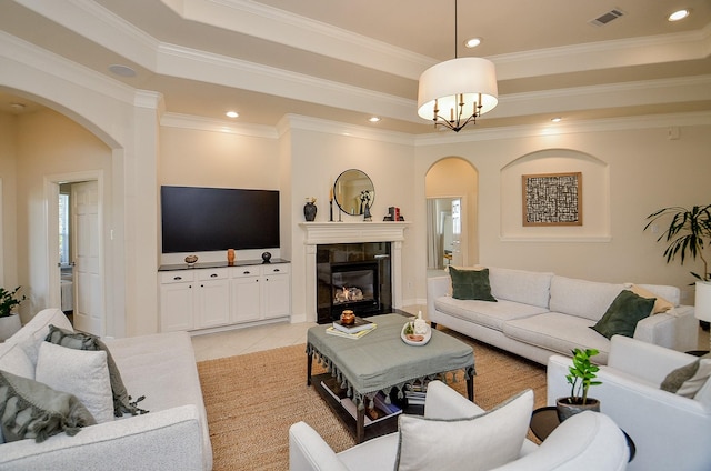 living room featuring crown molding, a fireplace, a tray ceiling, and light tile patterned floors