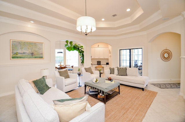 tiled living room with an inviting chandelier, a tray ceiling, plenty of natural light, and ornamental molding