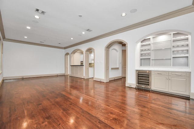 interior space featuring wine cooler, ornamental molding, built in shelves, and dark wood-type flooring