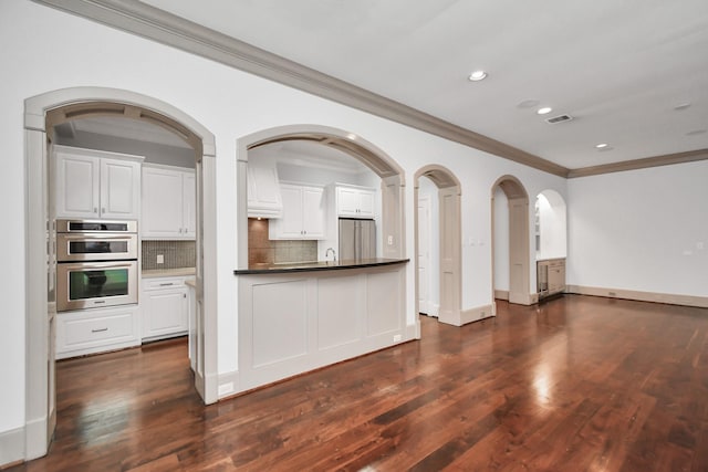 kitchen with white cabinetry, stainless steel appliances, dark hardwood / wood-style floors, and backsplash