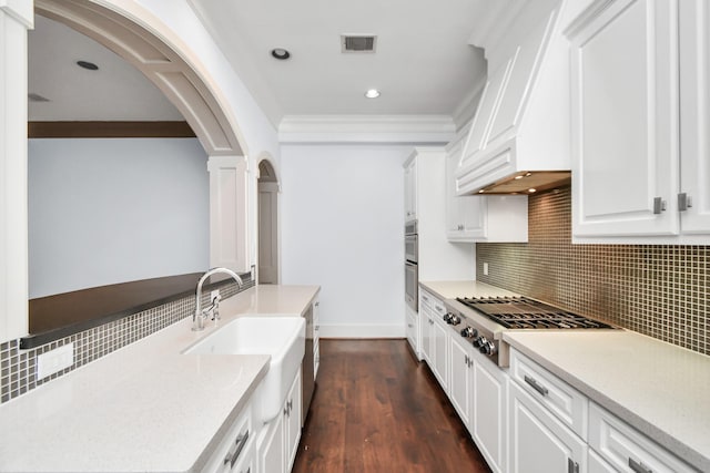 kitchen featuring stainless steel gas cooktop, ornamental molding, custom range hood, decorative backsplash, and white cabinets