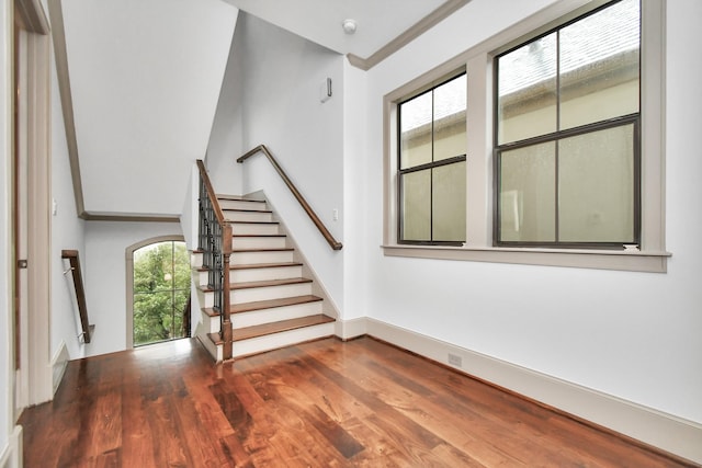 stairway with wood-type flooring, lofted ceiling, and ornamental molding