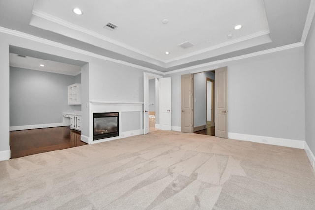 unfurnished living room featuring ornamental molding, a tray ceiling, and carpet