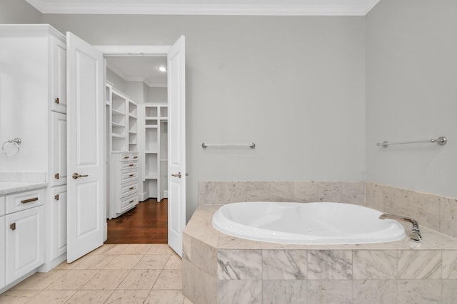 bathroom with tiled tub, crown molding, and tile patterned floors