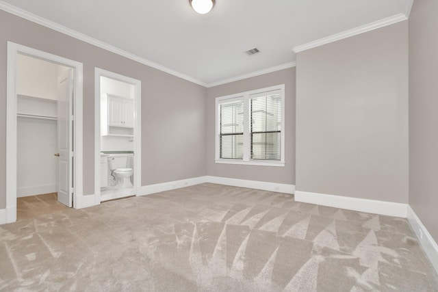 unfurnished bedroom featuring ornamental molding, a spacious closet, light colored carpet, and a closet