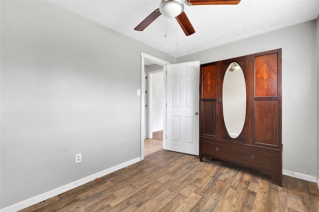 unfurnished bedroom featuring a textured ceiling, dark wood-type flooring, and ceiling fan