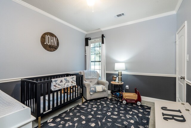 bedroom featuring crown molding, a nursery area, and carpet flooring