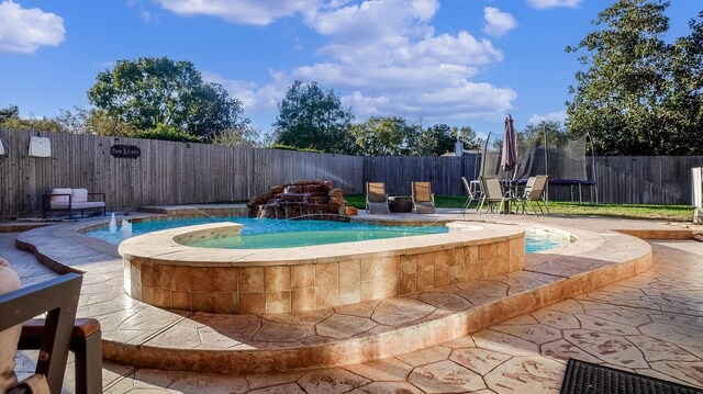 view of pool featuring a hot tub, pool water feature, and a trampoline